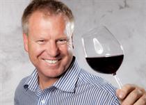 Glücklicher Mann mit gefüllten Rotwein-Weinglas in der Hand
