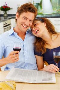 Lachendes Ehepaar trinkt alkoholfreien Wein in Küche